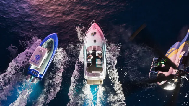 A topdown view of a Squalo moving through the water, with a police boat close by and a police helicopter overhead.